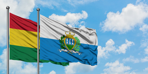 Bolivia and San Marino flag waving in the wind against white cloudy blue sky together. Diplomacy concept, international relations.