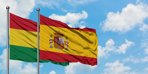 Bolivia and Spain flag waving in the wind against white cloudy blue sky together. Diplomacy concept, international relations.