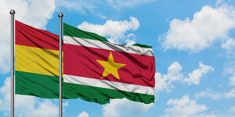 Bolivia and Suriname flag waving in the wind against white cloudy blue sky together. Diplomacy concept, international relations.