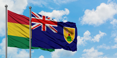 Bolivia and Turks And Caicos Islands flag waving in the wind against white cloudy blue sky together. Diplomacy concept, international relations.