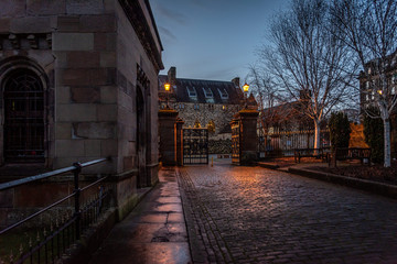 GLASGOW, SCOTLAND, DECEMBER 16, 2018: Beautiful cobbled street surrounded by old European style buildings. Illuminated only with weak light from street lamps.