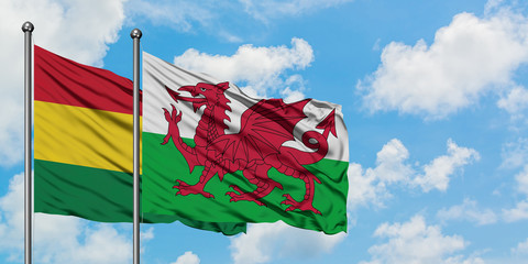 Bolivia and Wales flag waving in the wind against white cloudy blue sky together. Diplomacy...