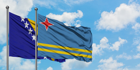 Bosnia Herzegovina and Aruba flag waving in the wind against white cloudy blue sky together. Diplomacy concept, international relations.