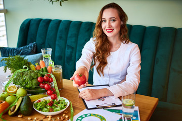 Woman dietitian in medical uniform with tape measure working on a diet plan sitting with different...