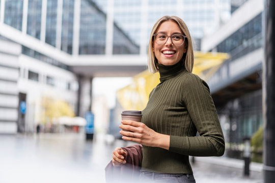 Happy young woman with takeaway coffee in the city