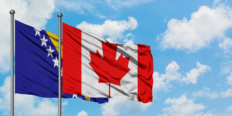 Bosnia Herzegovina and Canada flag waving in the wind against white cloudy blue sky together. Diplomacy concept, international relations.