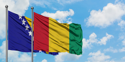 Bosnia Herzegovina and Guinea flag waving in the wind against white cloudy blue sky together. Diplomacy concept, international relations.