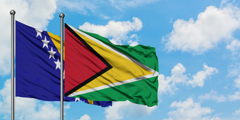 Bosnia Herzegovina and Guyana flag waving in the wind against white cloudy blue sky together. Diplomacy concept, international relations.