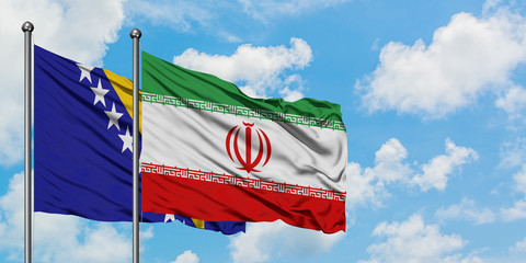 Bosnia Herzegovina and Iran flag waving in the wind against white cloudy blue sky together. Diplomacy concept, international relations.