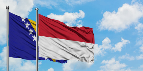Bosnia Herzegovina and Indonesia flag waving in the wind against white cloudy blue sky together. Diplomacy concept, international relations.