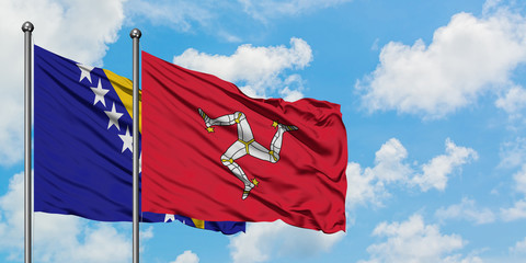 Bosnia Herzegovina and Isle Of Man flag waving in the wind against white cloudy blue sky together. Diplomacy concept, international relations.