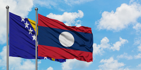 Bosnia Herzegovina and Laos flag waving in the wind against white cloudy blue sky together. Diplomacy concept, international relations.