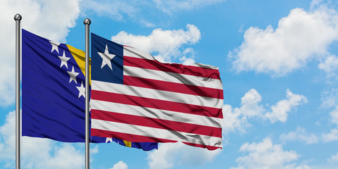 Bosnia Herzegovina and Liberia flag waving in the wind against white cloudy blue sky together. Diplomacy concept, international relations.
