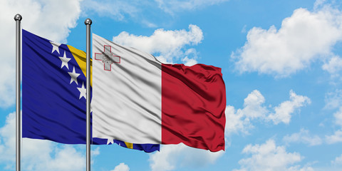 Bosnia Herzegovina and Malta flag waving in the wind against white cloudy blue sky together. Diplomacy concept, international relations.