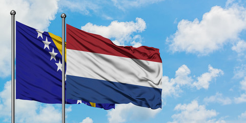 Bosnia Herzegovina and Netherlands flag waving in the wind against white cloudy blue sky together....