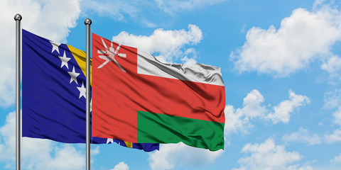 Bosnia Herzegovina and Oman flag waving in the wind against white cloudy blue sky together. Diplomacy concept, international relations.