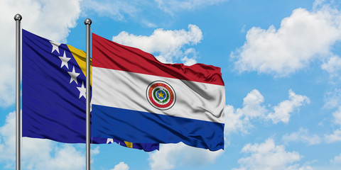 Bosnia Herzegovina and Paraguay flag waving in the wind against white cloudy blue sky together. Diplomacy concept, international relations.