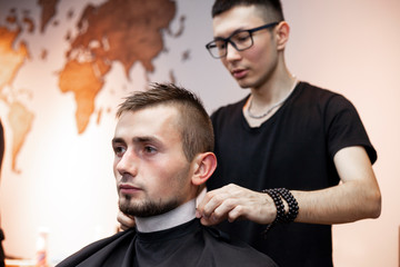 Kazakh barber gives the client a short haircut with a trimmer, a man has a haircut in a barbershop, guy does a hairstyle in a hairdresser