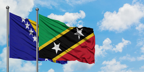 Bosnia Herzegovina and Saint Kitts And Nevis flag waving in the wind against white cloudy blue sky together. Diplomacy concept, international relations.