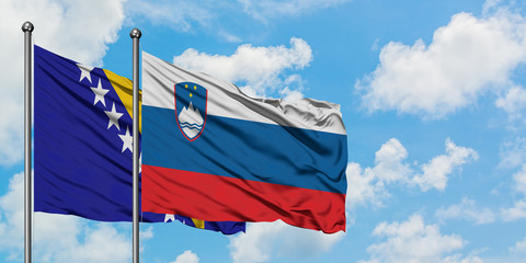 Bosnia Herzegovina and Slovenia flag waving in the wind against white cloudy blue sky together. Diplomacy concept, international relations.