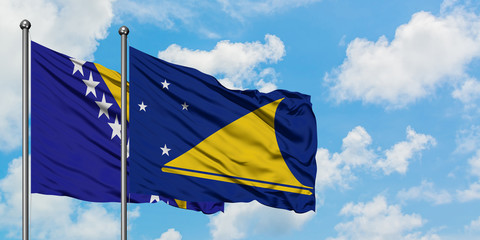 Bosnia Herzegovina and Tokelau flag waving in the wind against white cloudy blue sky together. Diplomacy concept, international relations.