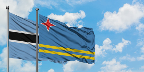 Botswana and Aruba flag waving in the wind against white cloudy blue sky together. Diplomacy concept, international relations.