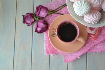 Russian marshmallowor zefir with pink cup of coffee on light teal wooden table. Top view, vintage style, dry roses. Empty place for positive or sentimental text