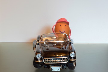An egg driving a  convertible car wearing a helmet as a symbol for road safety