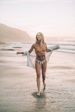 Young blond woman wearing bikini at the beach during sunrise