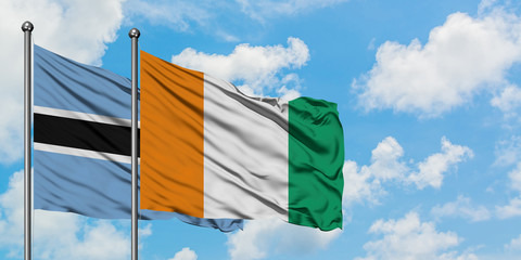 Botswana and Cote D'Ivoire flag waving in the wind against white cloudy blue sky together....