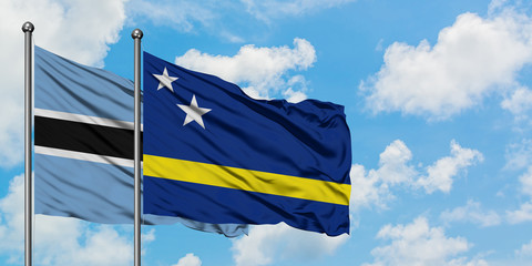 Botswana and Curacao flag waving in the wind against white cloudy blue sky together. Diplomacy concept, international relations.