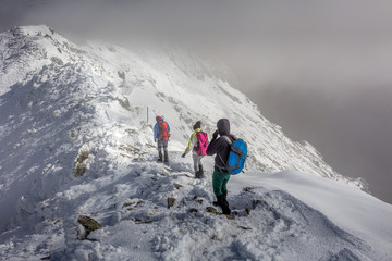 Three people make their way through the clouds at the Rila mountain in Bulgaria, Maliovica.