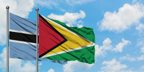 Botswana and Guyana flag waving in the wind against white cloudy blue sky together. Diplomacy concept, international relations.