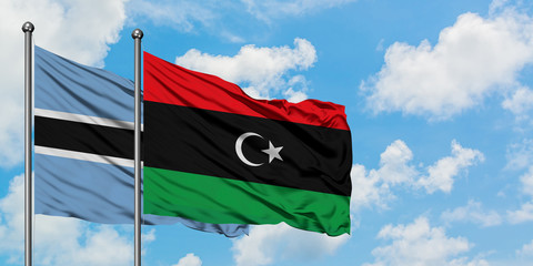 Botswana and Libya flag waving in the wind against white cloudy blue sky together. Diplomacy concept, international relations.