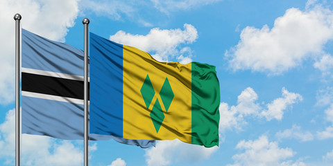 Botswana and Saint Vincent And The Grenadines flag waving in the wind against white cloudy blue sky...