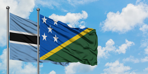 Botswana and Solomon Islands flag waving in the wind against white cloudy blue sky together. Diplomacy concept, international relations.