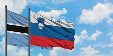 Botswana and Slovenia flag waving in the wind against white cloudy blue sky together. Diplomacy concept, international relations.