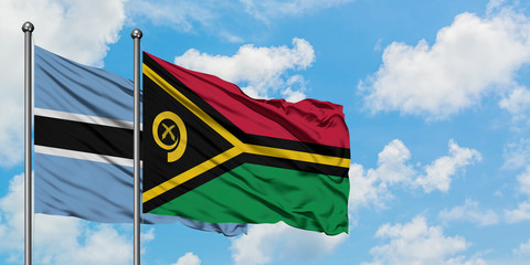 Botswana and Vanuatu flag waving in the wind against white cloudy blue sky together. Diplomacy...
