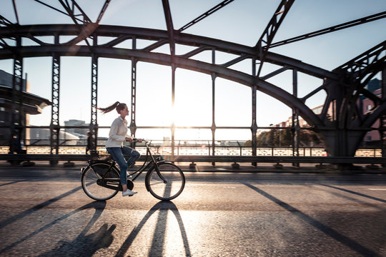 Young cyclist on a bridge at sunset