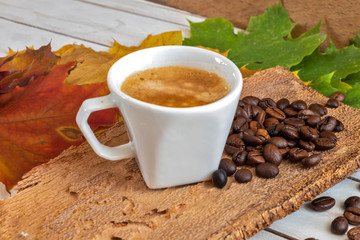 Cup and grain of coffee over different color autumn leave