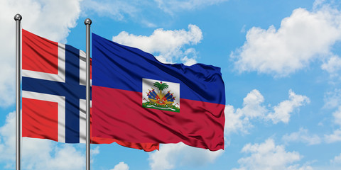 Bouvet Islands and Haiti flag waving in the wind against white cloudy blue sky together. Diplomacy concept, international relations.