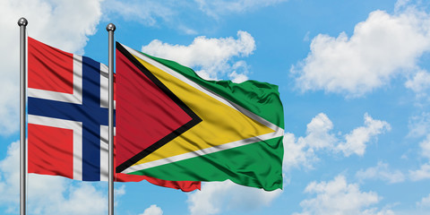 Bouvet Islands and Guyana flag waving in the wind against white cloudy blue sky together. Diplomacy concept, international relations.