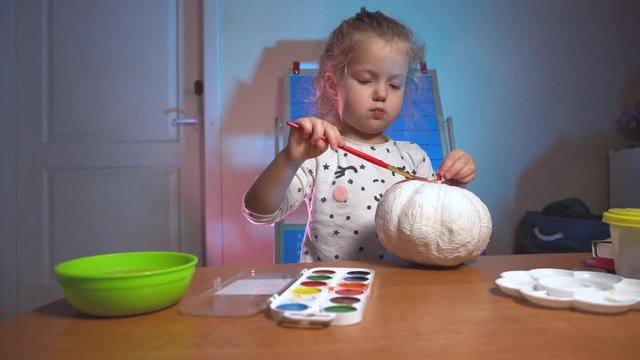 Little girl crafting some fake pumpking for halloween