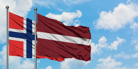 Bouvet Islands and Latvia flag waving in the wind against white cloudy blue sky together. Diplomacy concept, international relations.