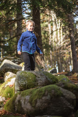 Obraz premium 7 year old boy walks on rocks in the mountain forest