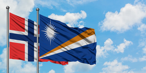 Bouvet Islands and Marshall Islands flag waving in the wind against white cloudy blue sky together. Diplomacy concept, international relations.