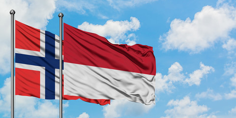 Bouvet Islands and Monaco flag waving in the wind against white cloudy blue sky together. Diplomacy concept, international relations.