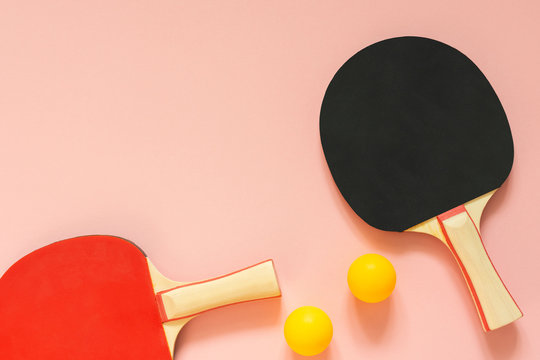 Black and red tennis ping pong rackets and orange balls isolated on a pink background, sport equipment for table tennis