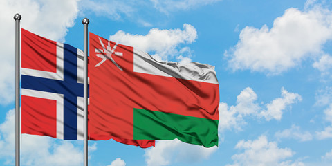 Bouvet Islands and Oman flag waving in the wind against white cloudy blue sky together. Diplomacy concept, international relations.