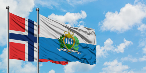 Bouvet Islands and San Marino flag waving in the wind against white cloudy blue sky together....